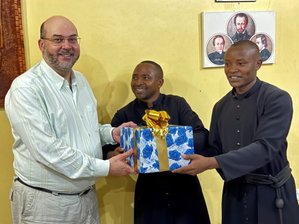 Fr. Evandro is presented with some small gifts by Valentino Chatanda and Livinus Galeba.